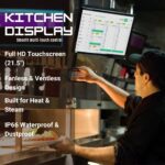 21.5 inch touchscreen kitchen display showing digital order management interface in a busy commercial kitchen